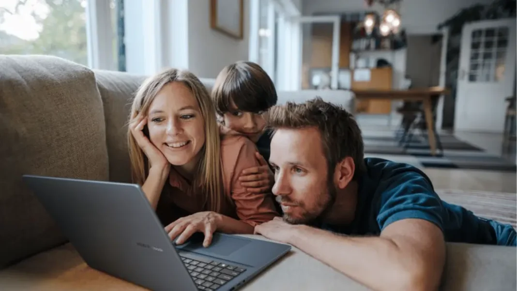 amily using ASUS VivoBook laptop on living room couch, demonstrating home productivity and entertainment features of the 2026 AI-powered laptop